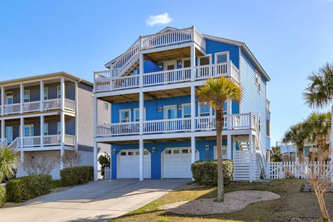 Coastal beach house with multiple balconies and tropical palm trees, perfect for family getaways near the shore.