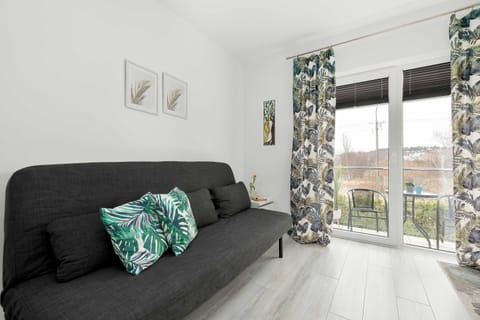 Another angle of the sofa area, showing more of the open-plan layout. The curtains and light flooring contribute to a calm, minimalist design.