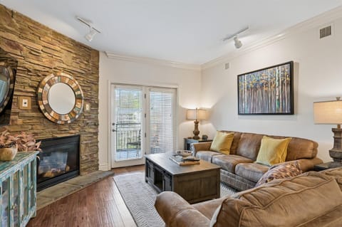 Unwind in your stylish living room featuring a cozy stone fireplace, plush leather seating, and warm lighting that creates the perfect atmosphere for relaxation.
