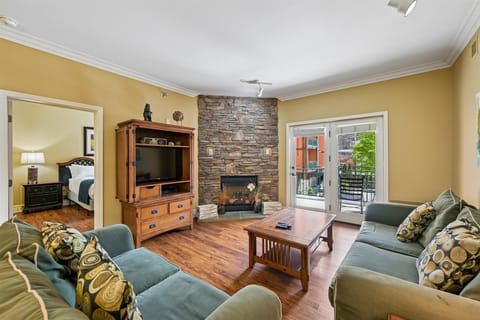 Unwind in your spacious living room with stone fireplace, comfortable seating, and balcony access overlooking peaceful surroundings.