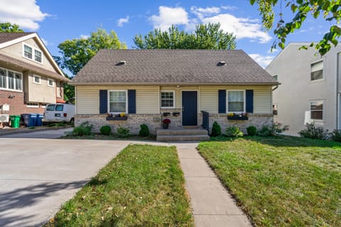Charming single-story home with blue shutters and stone accents sits in a quiet residential neighborhood with mature trees and spacious yard.