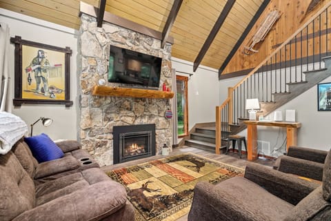 Cozy living room with stone propane fireplace, plush recliners, and vaulted A-frame ceilings