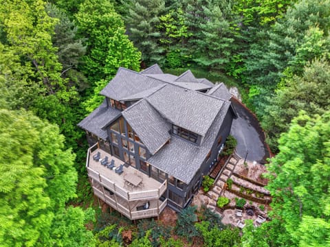 Secluded mountain retreat with expansive wraparound deck, surrounded by lush forest and scenic views.