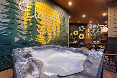 Soak in the hot tub beneath the “Unwind Under the Pines” mural—your own cozy, fun retreat after a day in Broken Bow.