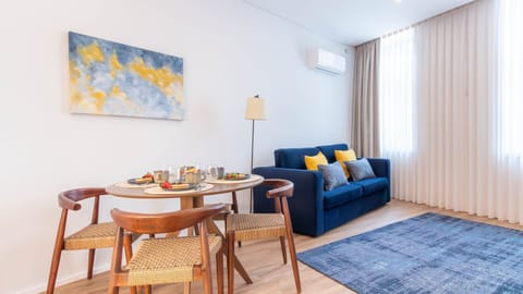 Cozy and inviting living area, complete with a dining table for a relaxing breakfast or dinner. The blue sofa and vibrant painting add a touch of comfort and style. #HomeyVibes #StylishLiving