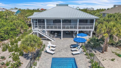 Spacious outdoor living area with shaded seating, lounge chairs, and a resort-style pool—perfect for group getaways and family time..
