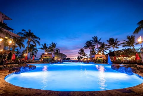 Tropical twilight glow over a serene, torch-lit resort pool. HKH-222