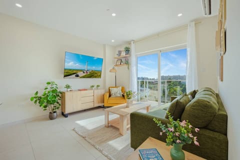 Bright and cozy living area with a smart TV, comfortable seating, and sliding doors that open to a private balcony with open island views.