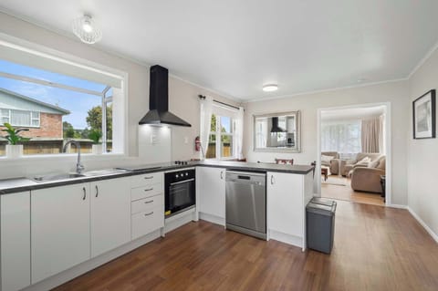 Fully equipped kitchen with oven, stainless dishwasher, black rangehood, and open-plan connection to the lounge — modern Rotorua rental