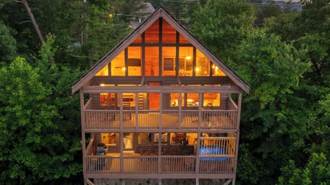 Three stories of warm golden light glowing out of the forest at dusk — when the mountains go quiet, this is home.
