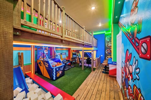 Step into this vibrant playroom, where colorful murals energize the space and a soft green turf invites playful adventures. Enjoy a variety of arcade games and a cozy loft area, perfect for kids to explore and enjoy.