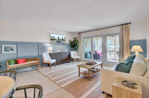 Bright coastal‑inspired living room with relaxed seating, natural textures, and easy flow to the screened porch.