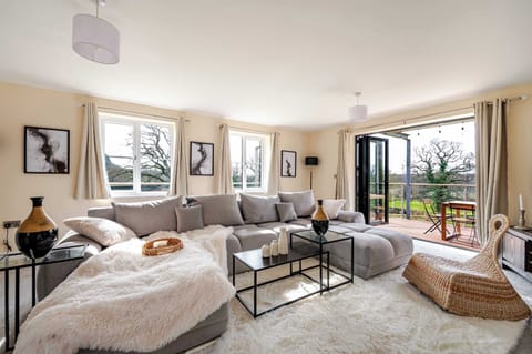 Sunlit and spacious, this living room features a plush sectional, cozy textures, and a flat screen smart TV, perfect for unwinding with streaming or enjoying the serene outdoor views
