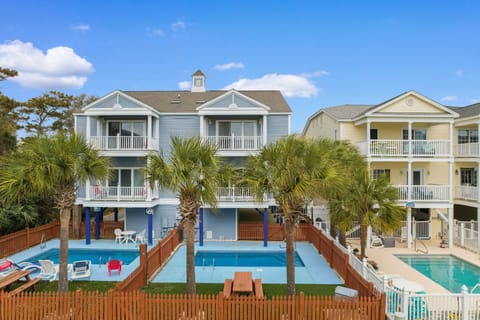 Coastal vacation homes featuring private pools surrounded by tropical palms create the perfect beach getaway atmosphere.