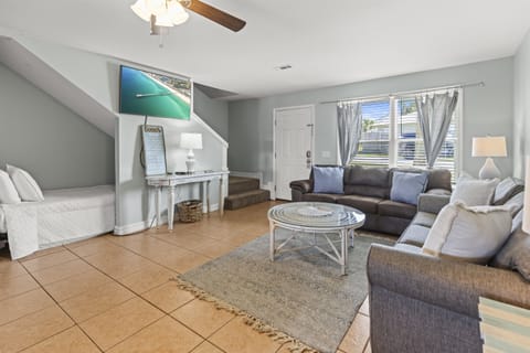 Unwind in your bright, coastal living room with plush seating, entertainment center, and serene ocean artwork to set your vacation mood.