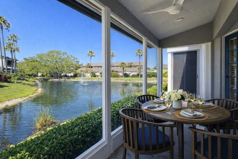 Screened lanai with dining table and chairs overlooking a tranquil lake, with open views of the surrounding landscape