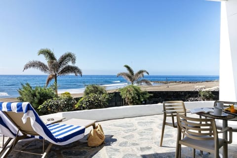 Sunny terrace with sun loungers, dining table and direct sea views.