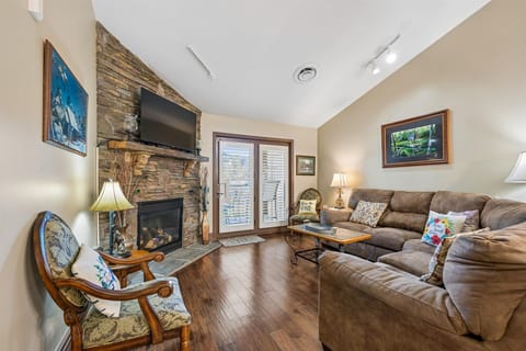 Unwind in your cozy living room with plush leather seating, warm fireplace, and mountain artwork creating the perfect retreat atmosphere.