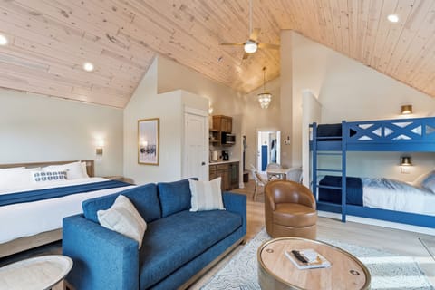 Soaring wood ceilings add warmth to your spacious suite, where a cozy living area, queen bed, and custom bunk beds create the perfect setup for families or groups seeking comfort and togetherness.