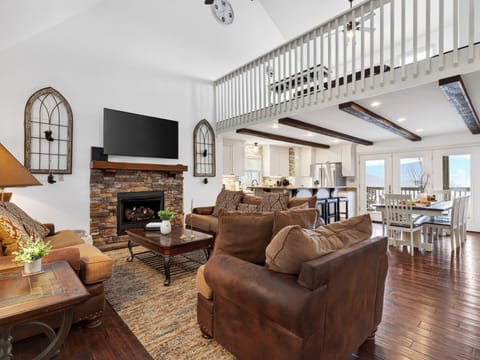 Spacious living room with a stone fireplace, leather seating, and a loft overlook.