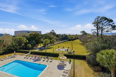 Poolside Living with Beach Access- 300 Shipwatch - The resort-style community pool offers a relaxing space with ample lounge seating and a peaceful setting. Just beyond, a scenic path leads to the beach for an easy coastal stroll.