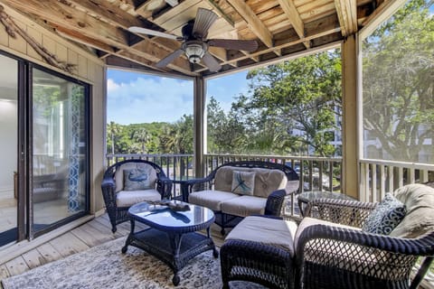 Unwind on your private covered balcony with comfortable wicker seating, a ceiling fan, and serene views of lush greenery—your perfect spot to relax with morning coffee or evening conversation.