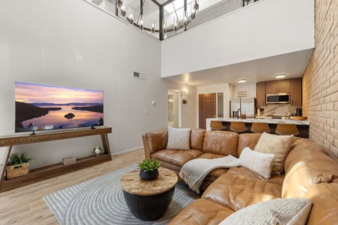 Open-concept living area with marble kitchen island, stone fireplace, and vaulted ceilings