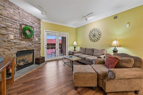 Relax in your spacious living room featuring cozy sectional seating, elegant fireplace, and private balcony access for perfect evenings.