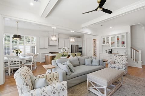 Relax in this bright, open living space where coastal elegance meets comfort, featuring plush seating and seamless kitchen flow.