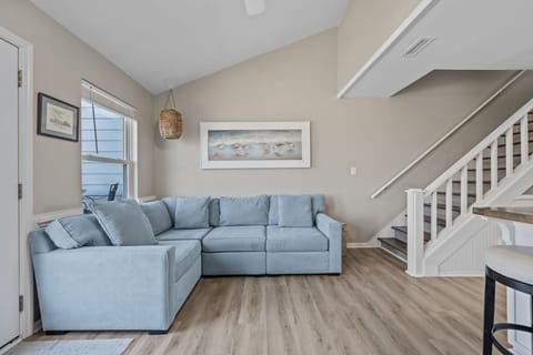 Relax in the bright coastal living area with a spacious sectional — the perfect spot to unwind after a day at the beach
