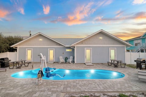Stunning vacation rental with private pool and patio seating areas at sunset.