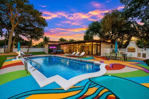 Colorful poolside area with lounge chairs and an outdoor dining space at sunset