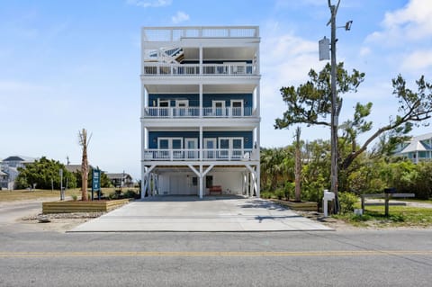 Modern four-story beach house featuring multiple balconies and elevated design, situated in a coastal residential neighborhood with convenient parking.