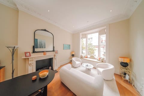 A bright living room with white modern seating, a fireplace, and a large bay window.