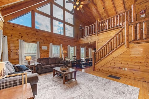 Unwind in your spacious log cabin living room with soaring ceilings and natural light streaming through grand windows.