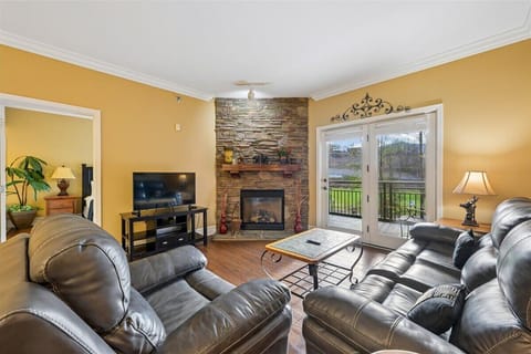 Sink into plush leather seating by your cozy stone fireplace, where warm golden walls and French doors invite relaxation.