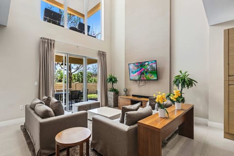 Spacious living room with high ceilings and large windows overlooking the outdoor patio.