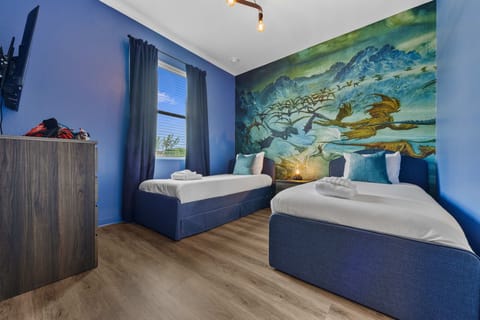 Twin beds in a themed room with a dragon mural and natural light from the window