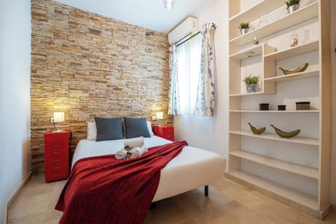 Unwind in this stylish bedroom featuring a rustic stone accent wall, comfortable double bed, and modern air conditioning.