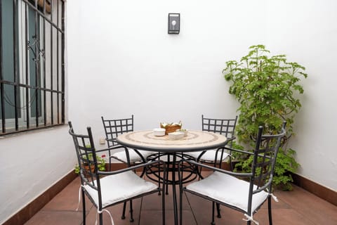 Unwind in a serene, private Andalusian courtyard. A mosaic table and wrought-iron chairs invite elegant al fresco dining.