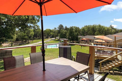 Private deck with red umbrella and outdoor dining table overlooking resort pool and grounds