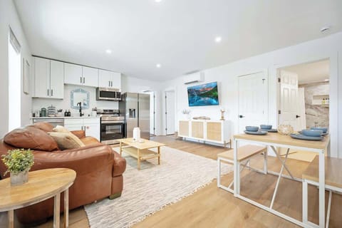 large living room, dining area and kitchen, with outdoor seating on the patio just right outside the front door.