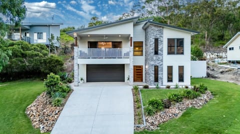 Contemporary house featuring spacious balcony, double garage, and landscaped entry, perfect for family comfort.