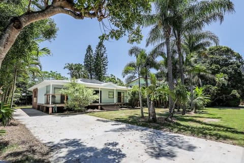 Single‑story beachfront home with tropical landscaping, solar‑panel roof, and front porch. Spacious, family‑friendly setting.