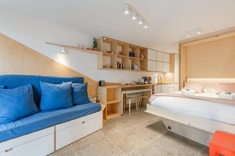 Modern studio with a blue sofa and built-in shelving for a comfortable stay