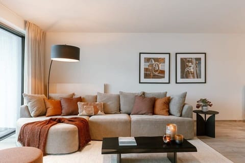 Modern living room with a spacious beige sectional sofa and warm-toned accents.