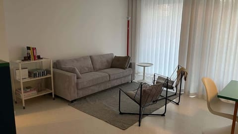 Modern living area with a comfortable sofa and natural light from large windows.