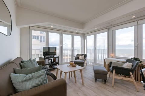 Relax in this bright living room with panoramic ocean views through floor-to-ceiling windows.