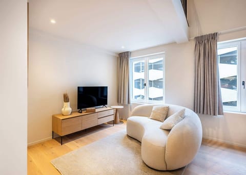 Modern living room with a curved sofa and natural wood media console.