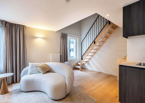 Modern living area with a curved sofa and wooden staircase leading to the upper level